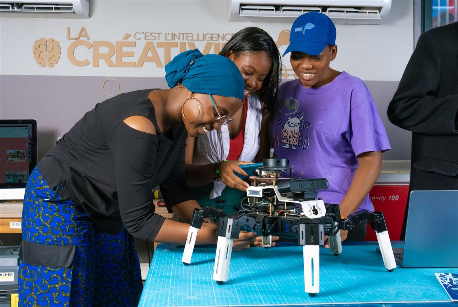 Trois membres de l'équipe testent un robot hexapode dans le makerspace
