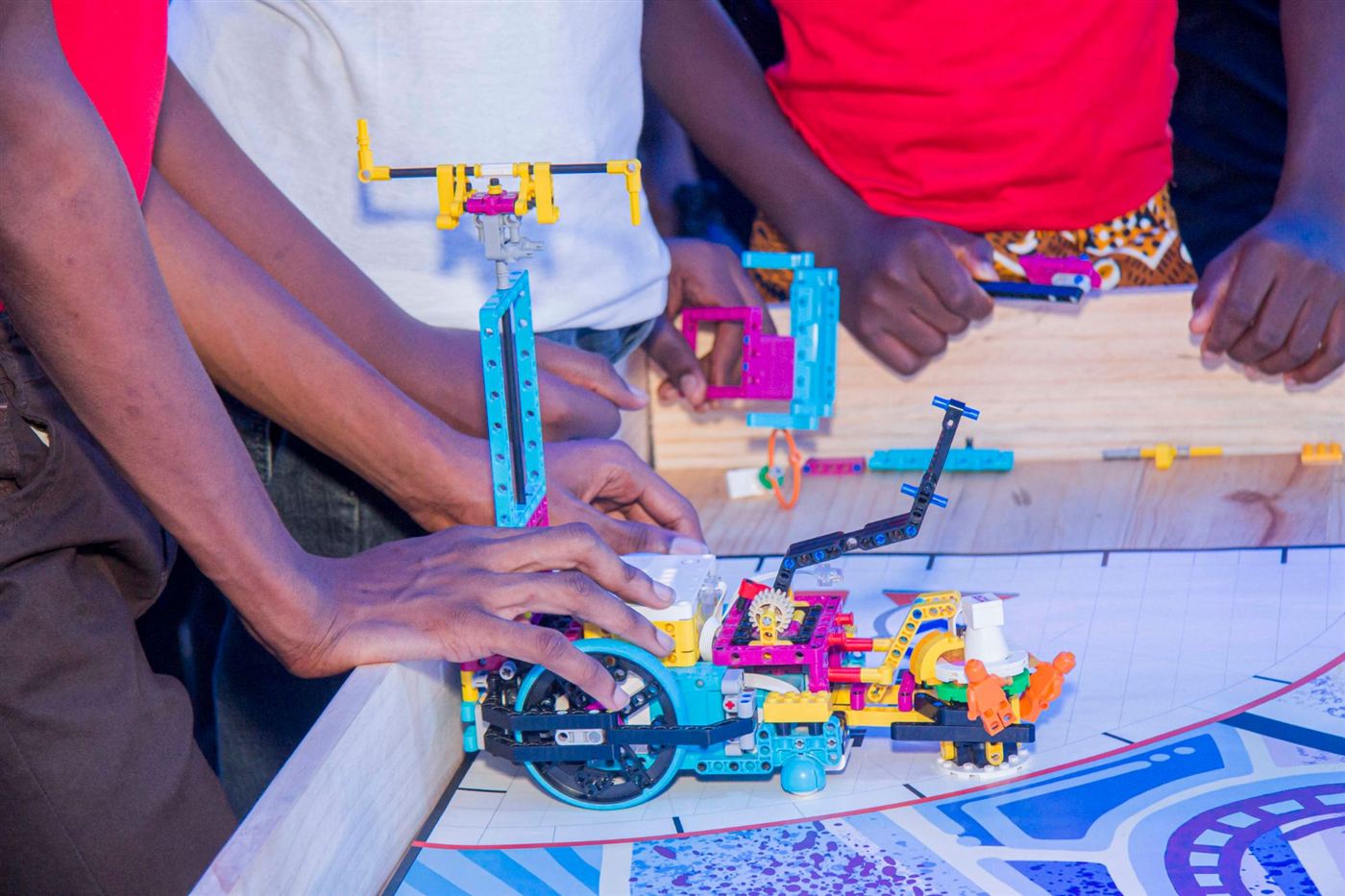 Gros plan sur un robot LEGO prêt à partir, entouré des mains des élèves