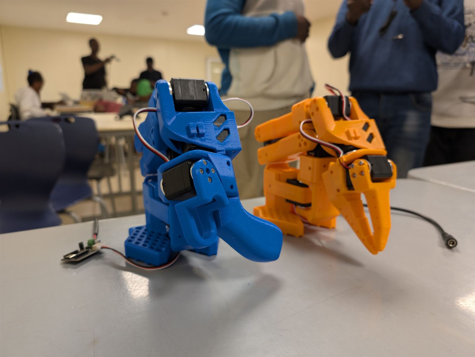 Un bras leader bleu et un bras follower orange assemblés pendant le LeRobot Hackathon